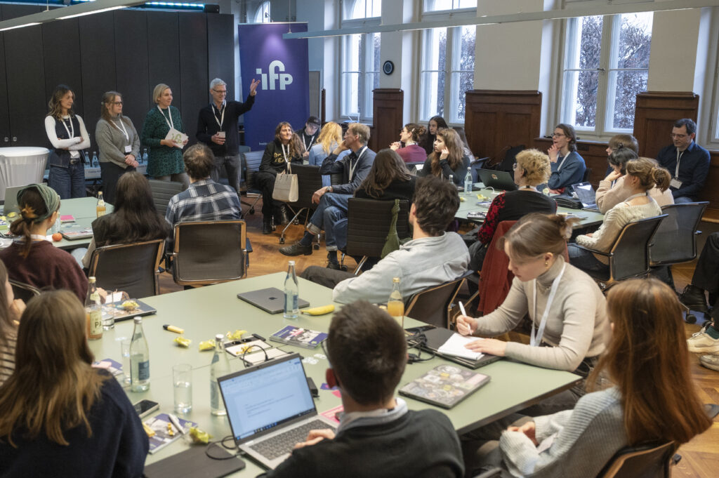 Ein Raum, in dem etwa 20 Personen den vier Gastgebern zuhören