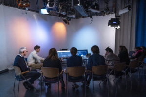 Neun Personen sehen sich auf einem großen Monitor eine Software-Demo an.